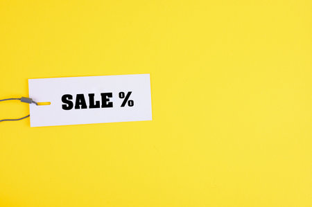 A closeup of a sale tage on a yellow background