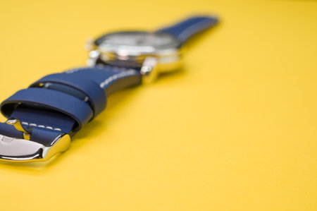 A closeup shot of a black classic wrist watch isolated on a yellow backgroundの写真素材