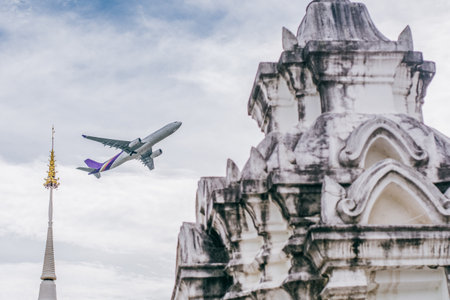 A low angle shot of a plane flying over the White Temple in Chiang Maiの写真素材