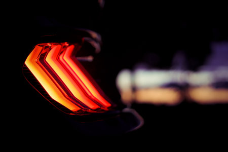 A closeup shot of a black sports car red backlight at nightの写真素材