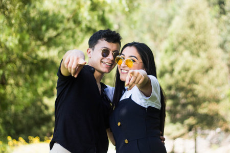 A shallow focus shot of a happy couple pointing at the cameraの写真素材
