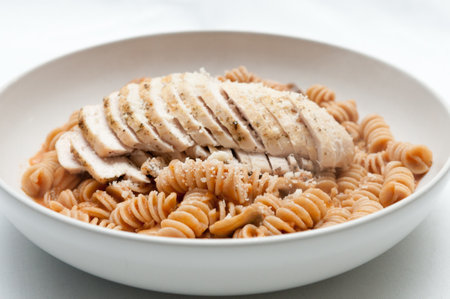 sliced chicken breast over rotini noodles with a tomato cream sauceの写真素材