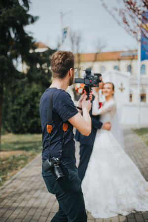 A shallow focus shot of a wedding photographer takes pictures of the bride and groomの写真素材
