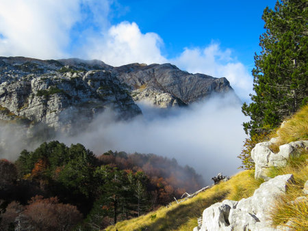 A mesmerizing view of the rocky landscapes covered with clouds captured from a peakの写真素材