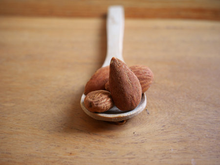 A selective focus shot of roasted almonds on a white spoon on aの写真素材