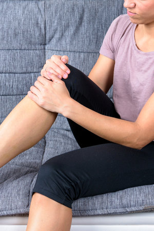 Young muscular woman has knee pain due to too much trainingの写真素材