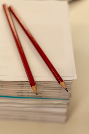 A vertical shot of two pencils on a pile of papersの写真素材