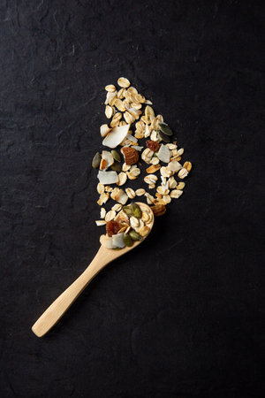 A vertical shot of healthy and delicious spooned muesli on a black backgroundの写真素材