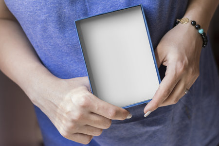 A close-up shot of female hands holding a white and blue gift box