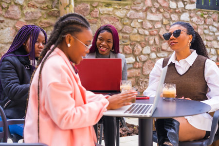 The young African-American females at a business meeting in a cafeteria with laptops and coffee on the tableの写真素材