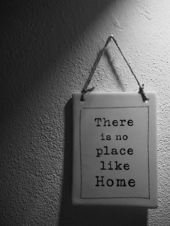The âThere is no place like Homeâ writing on a small plate hanging on the wall shot in grayscaleの写真素材