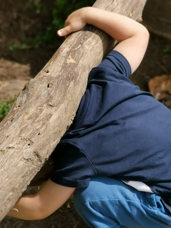 A vertical closeup shot of a male picking up a tree trunkの写真素材