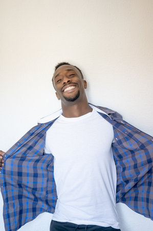 A vertial shot of a happy handsome Black man wearing a blue shirtの写真素材