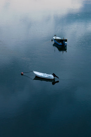 A vertical shot of anchored sailboats on a calm waterの写真素材