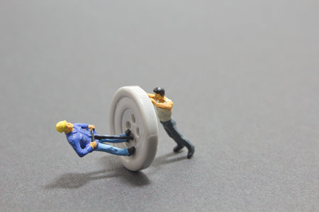 A closeup shot of small figures of workers on a white button