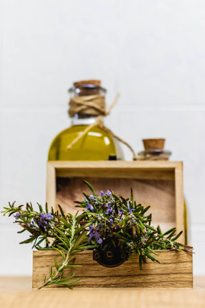 A closeup of rosemary in a wooden box with a bottle of rosemary oil on the backgroundの写真素材
