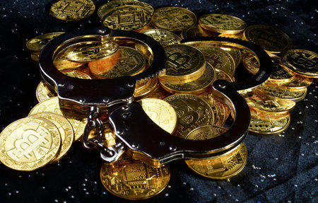 A pile of gold coins with a pair of handcuffs on a black background; theft, crime, or fraudの写真素材