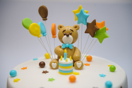 A closeup shot of a birthday cake with decorations of balloons, stars and a bearの写真素材