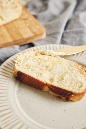 A vertical shot of delicious sweet yeast bread slice with butter on a white table
