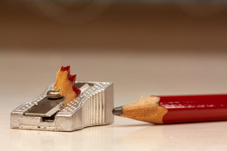 A closeup shot of a metal sharpener and a red pencil on a white backgroundの写真素材