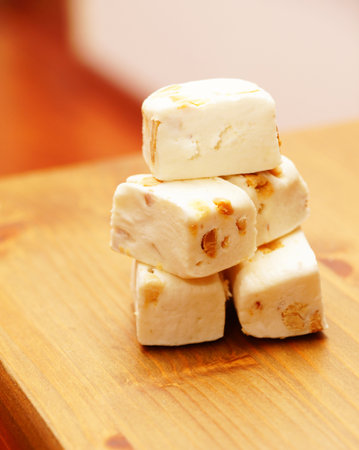 A vertical shot of soft nougat with peanuts and fruits in a wooden tableの写真素材