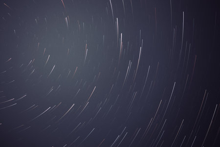 A horizontal background of star trails on a dark blue skyの写真素材