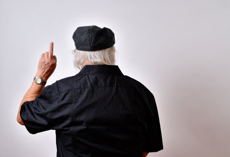 An American old man showing contempt with his back to the camera and one hand showing the middle fingerの写真素材