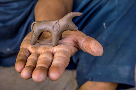 A closeup shot of a hand holding a clay figurineの写真素材