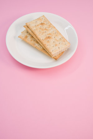 A vertical shot of a plate with salty crackers on a pink surfaceの写真素材