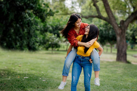 Two gorgeous cheerful young girlfriends from Argentina enjoying their day in a park on a sunny dayの写真素材
