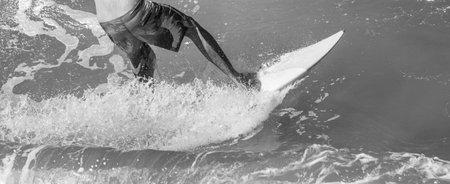 A grayscale shot of a person surfing on the wavesの写真素材