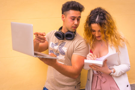 A young entrepreneur couple doing teamwork against a yellow wallの写真素材