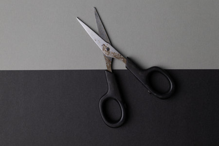 A top view of metal rusty scissors wide open on a black and gray backgroundの写真素材