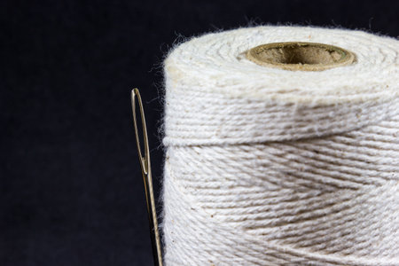 A twine roll with a needle in the black background with copy space on the left