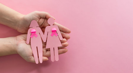 A top view shot of female hands holding girl silhouettes with pink ribbonsの写真素材