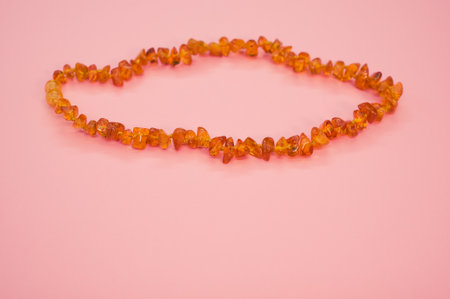 A closeup shot of an amber beads necklace on a pink surfaceの写真素材