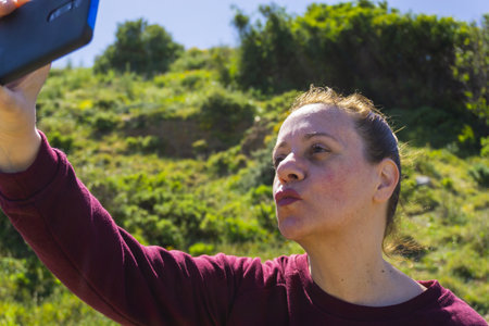A closeup shot of a Caucasian female taking selfie outside on a sunny day