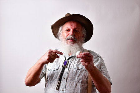 A senior Caucasian bearded male holding an egg in his left handの写真素材