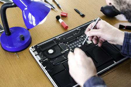 A technician's hands repairing disassembled laptopの写真素材