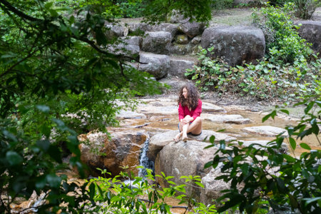 A young Caucasian female sitting on a stone in a lakeの写真素材