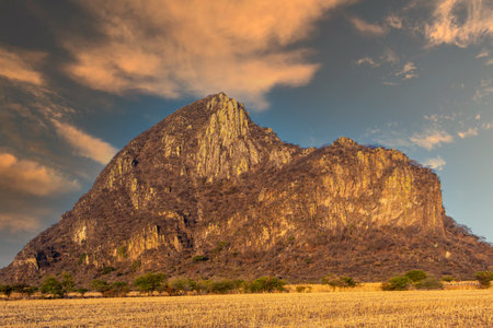A beautiful view of a giant rocky cliff on a grassy field under a cloudy skyの写真素材