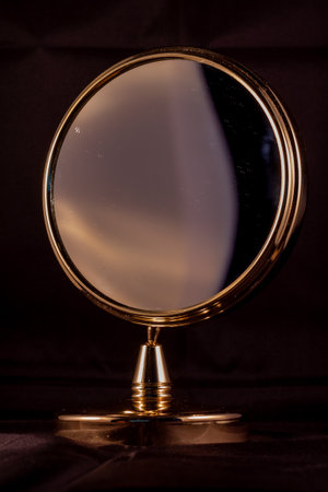 A vertical shot of a golden framed round mirrorの写真素材