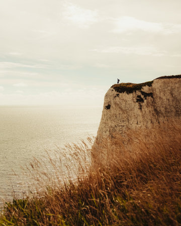 A vertical of a person on a cliff near the seaの写真素材
