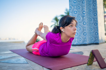 A Hispanic female practicing yoga outdoors