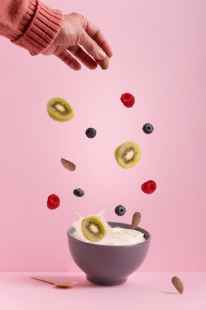 A vertical shot of different fruits and berries falling into a bowl of milk on a pink backgroundの写真素材