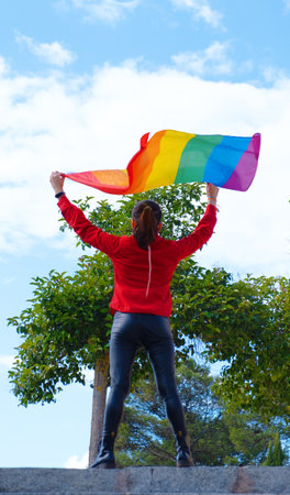 A vertical shot of a Caucasian transgender girl with the gay flag at  Gay Pride Dayの写真素材