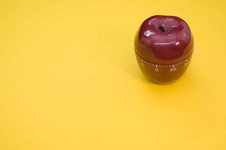 An apple-shaped kitchen timer isolated on yellow backgroundの写真素材