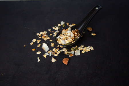 A healthy and delicious spooned muesli on a black backgroundの写真素材