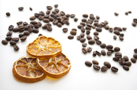 A closeup of the roasted coffee beans with dried lemons on the white surfaceの写真素材