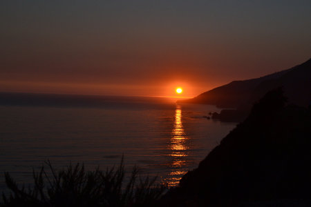 A beautiful scenery of a calm sea with the reflection of the sun on the surface during sunsetの写真素材
